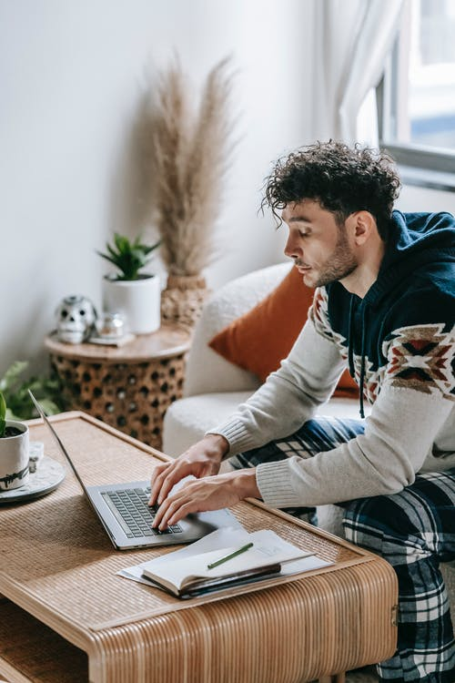 A person working on a laptop while making notes