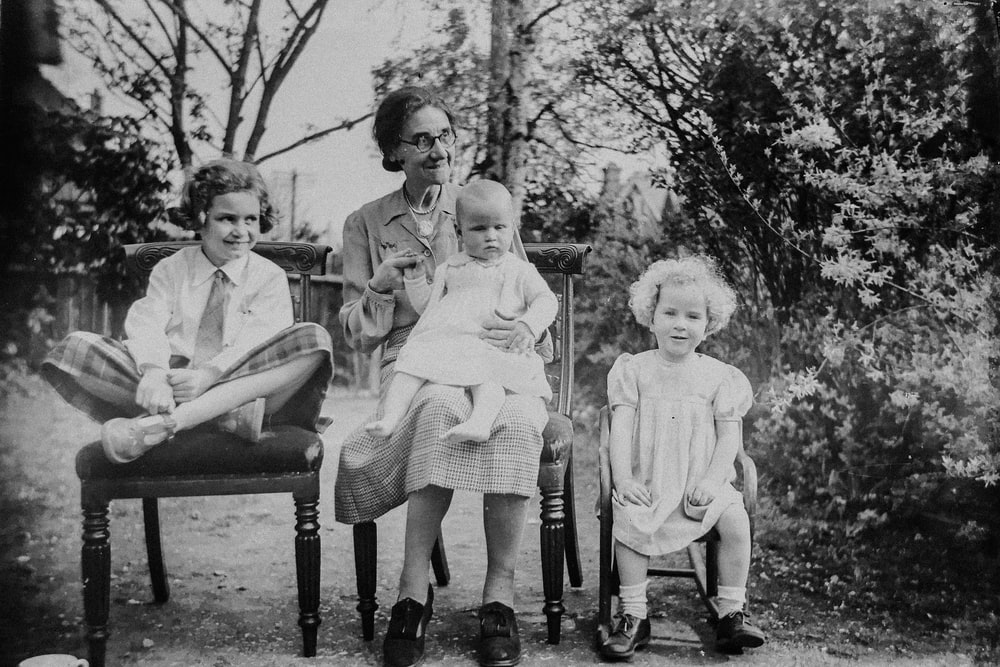 An old black and white photograph of an old lady with 3 children