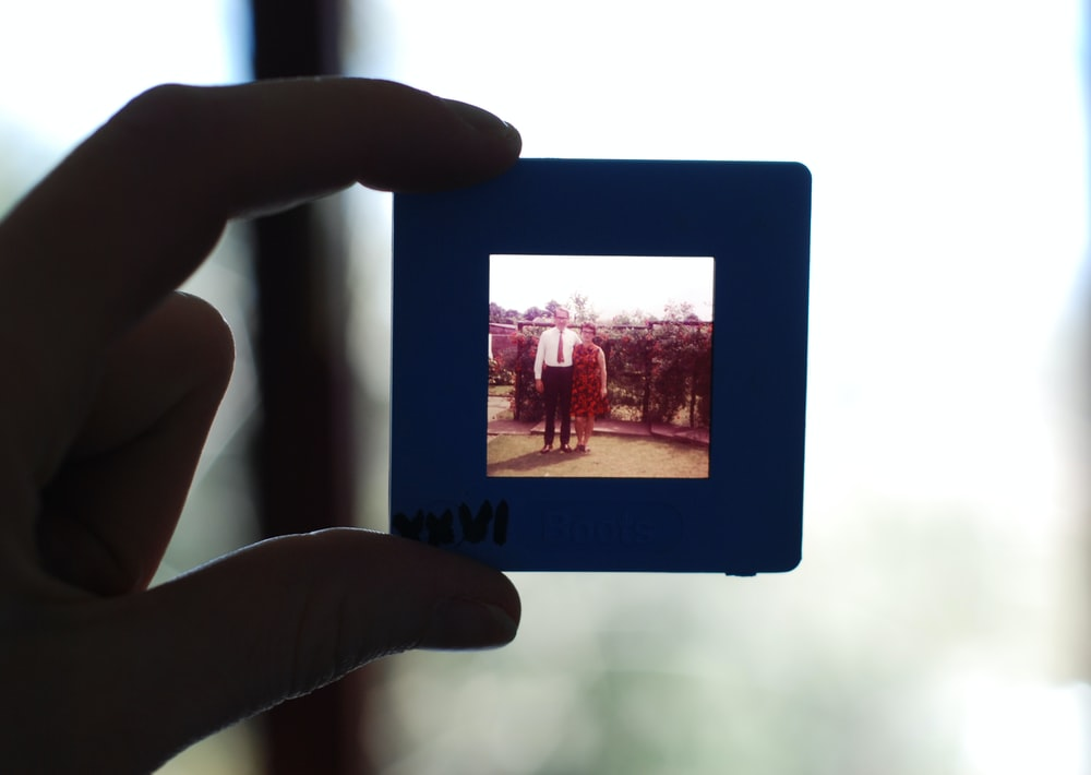 A person holding a small square photograph