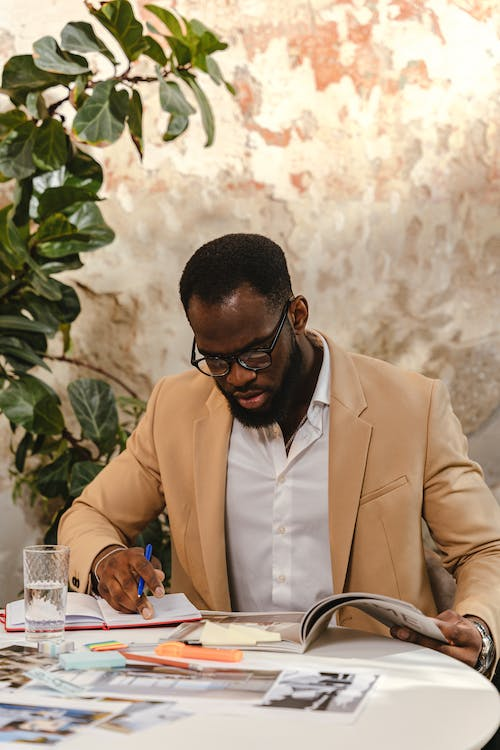 A person making notes while reading from a magazine