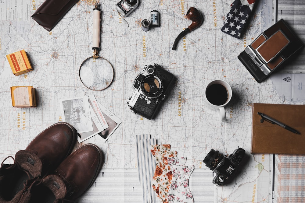 Shoes, cameras, a notebook, and a magnifying glass on a map