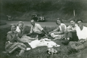 A black and white photo of a group of people having a picnic  