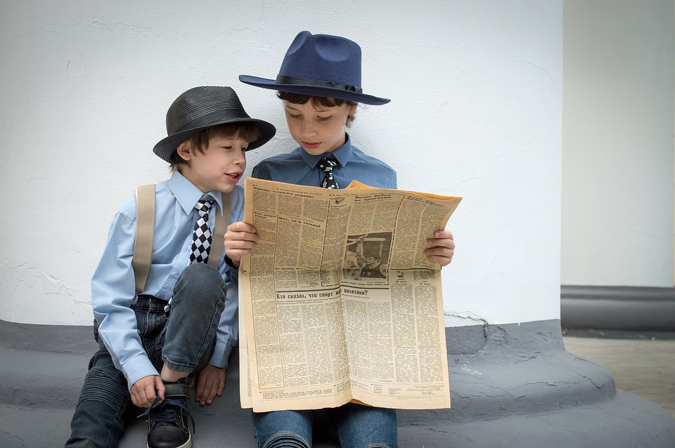 Two little boys reading an old newspaper