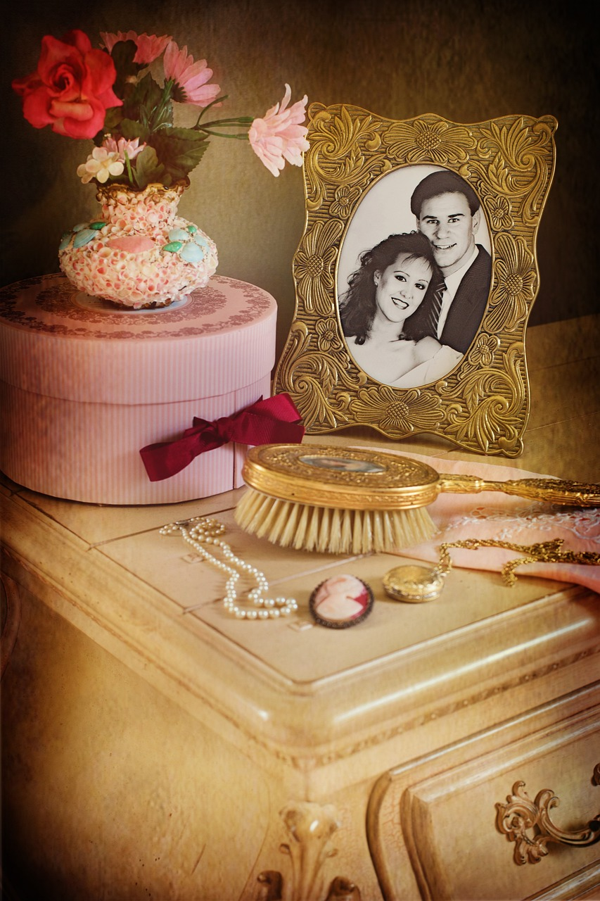 A framed black and white photo of a couple next to an antique brush on a dresser  
