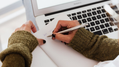 A person taking notes while working on a laptop