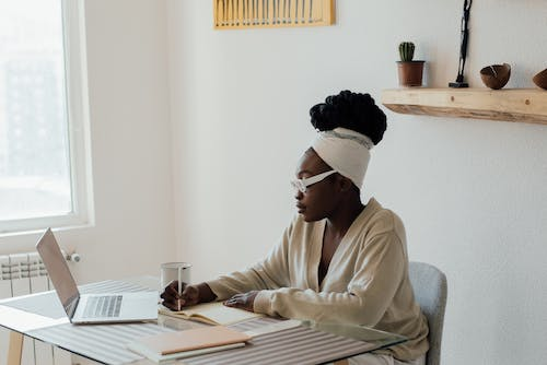 A person taking notes while working on a laptop