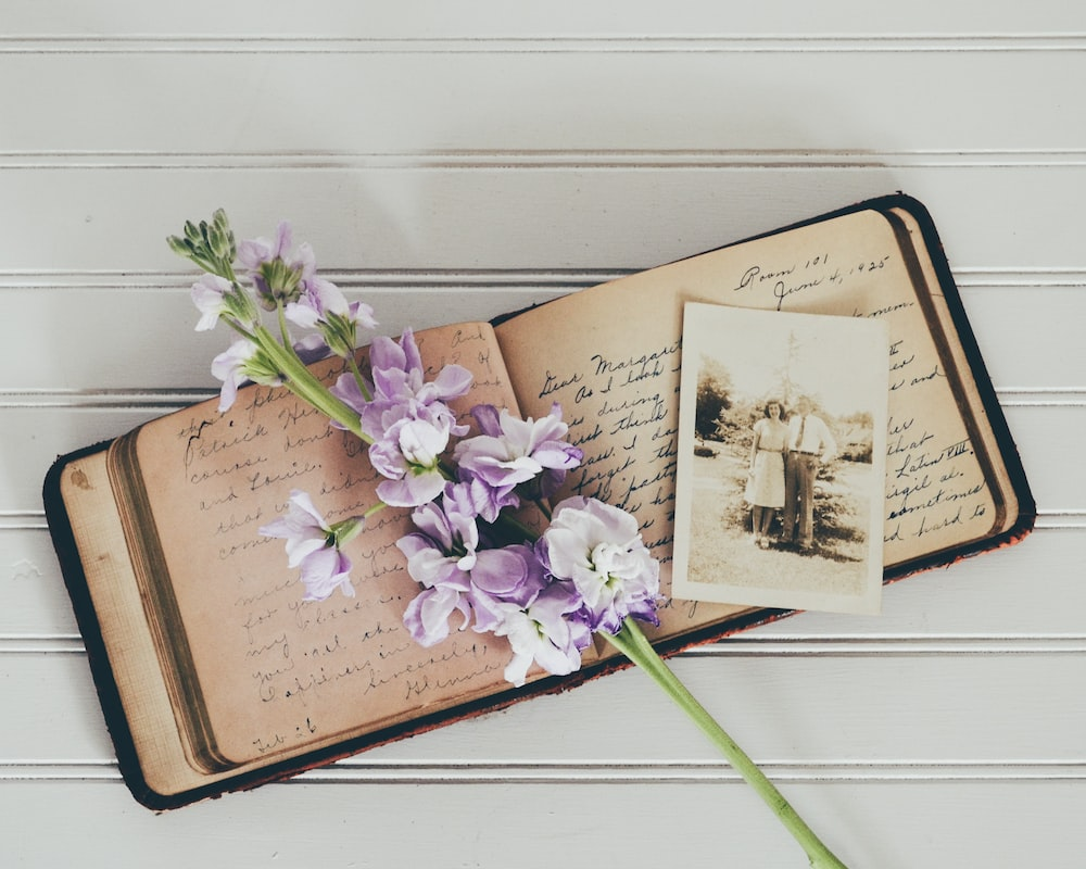 An old open journal with an old photograph and flowers placed on it