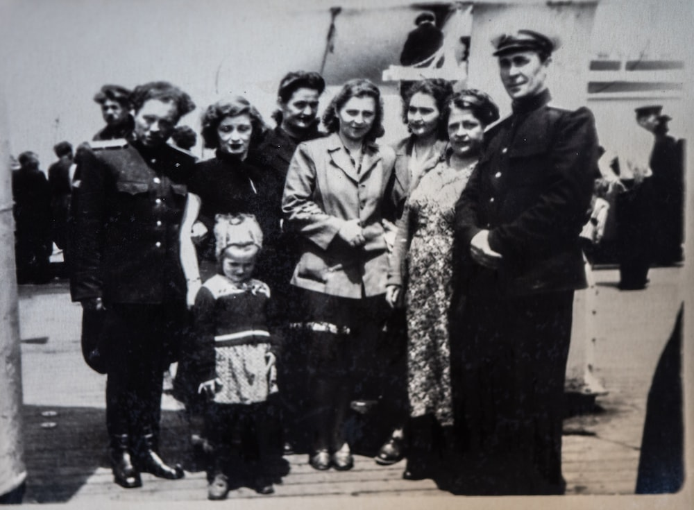 A grey-scale photo of several women, men in uniform, and a child