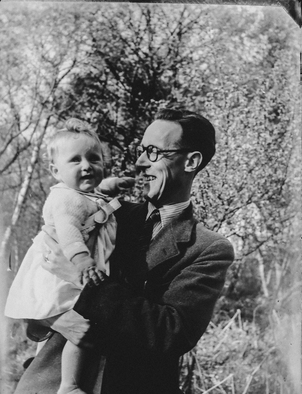 A man smiling and holding a smiling child illustrating DNA inheritance in genealogy