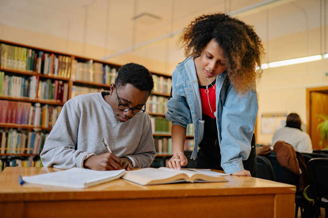 two people writing at the library.