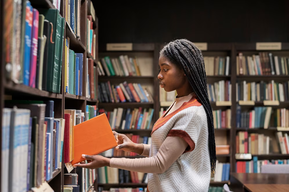 a girl holding a book in a library.