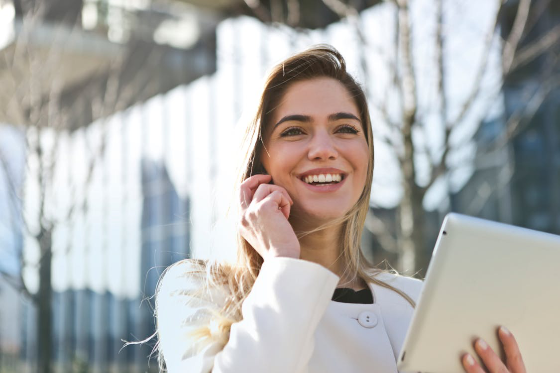 a woman smiling and standing outdoors.