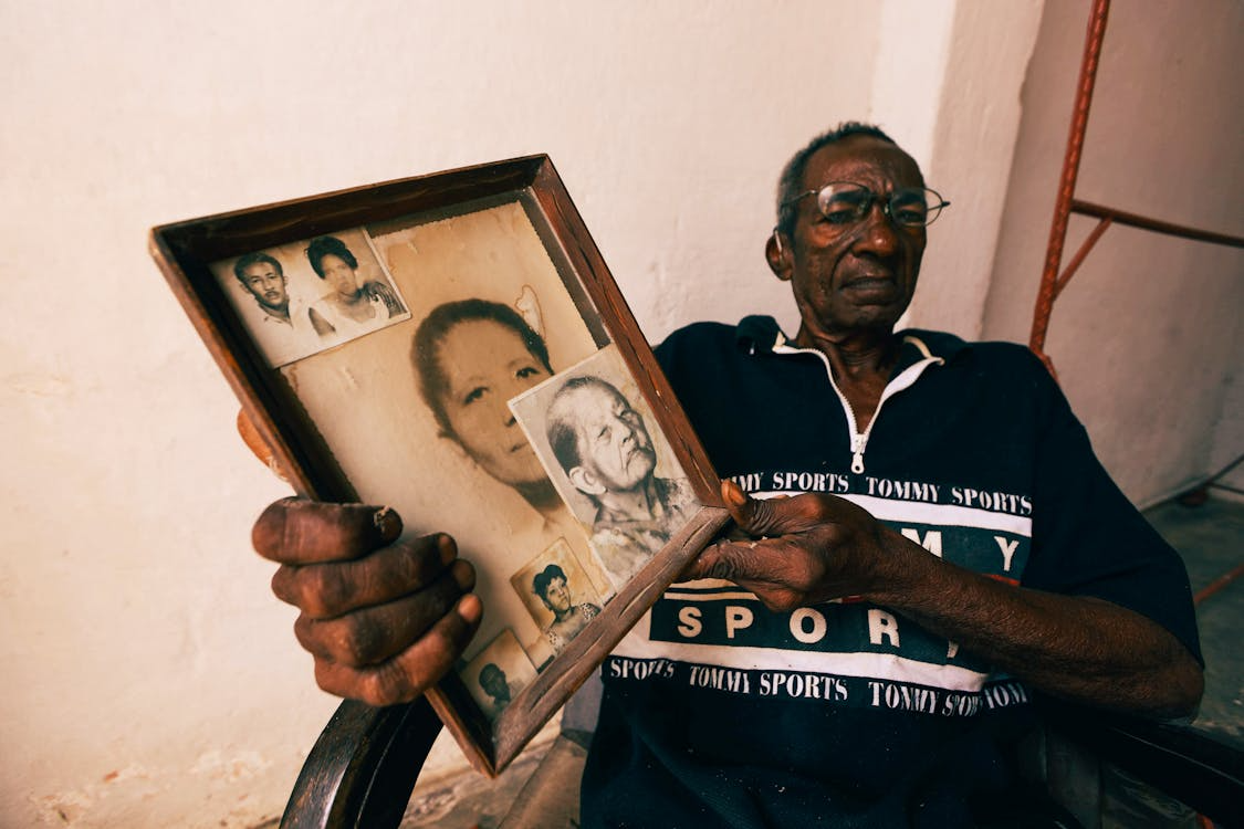 an elderly man holding a portrait.
