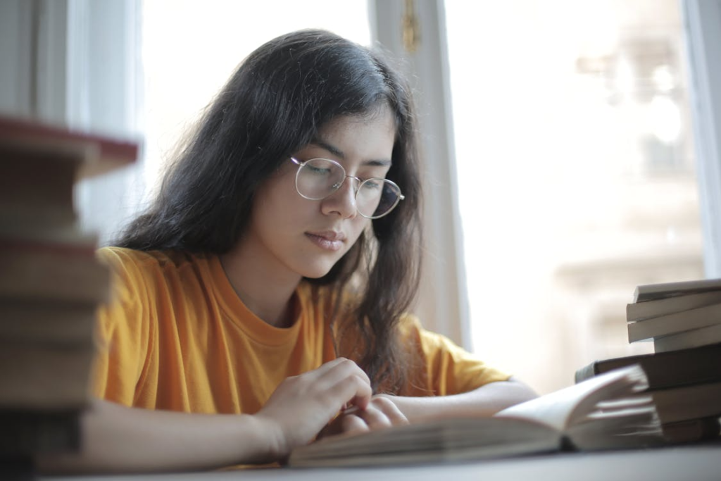 a woman in a yellow shirt reading a book.