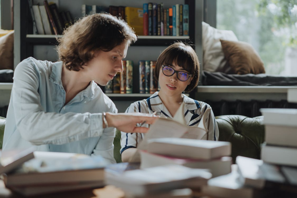 two people sitting and reading a book.
