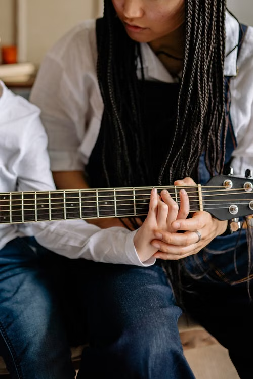 a woman learning to play the guitar.